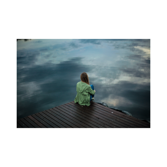 A woman in her 40s sitting quietly at a window with a Soothe Organic CBD tincture and a cup of tea, looking calm and present
