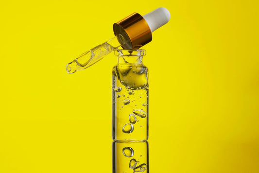 Close-up of a dropper releasing clear water-soluble CBD liquid under a person’s tongue, with soft natural light and a calm wood background.
