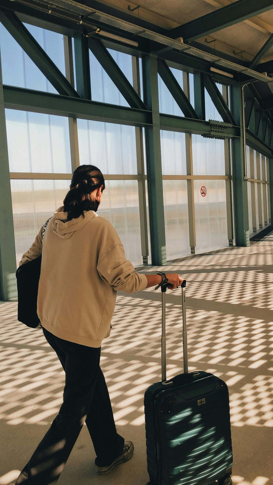 An open carry-on suitcase on a bed at sunrise with a Soothe Organic USDA Certified Organic CBD tincture and broad-spectrum CBD gummies alongside a boarding pass and passport, representing traveling with CBD in 2026