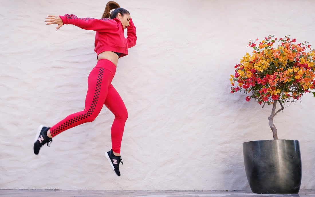 Woman in Red Tracksuit Jumping Near Wall