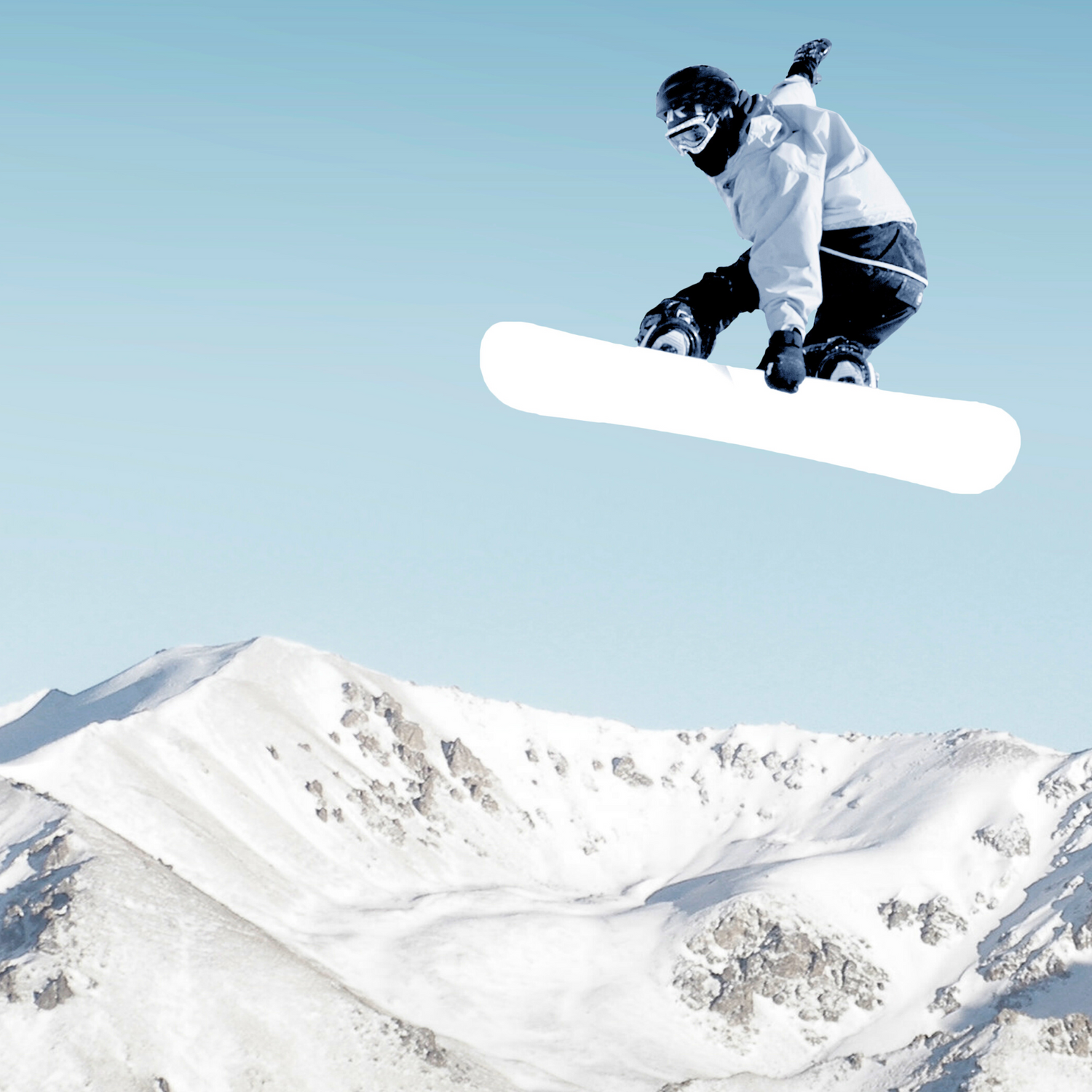 A snowboarder catches air while jumping off a snowy slope with breathtaking mountain peaks in the background
